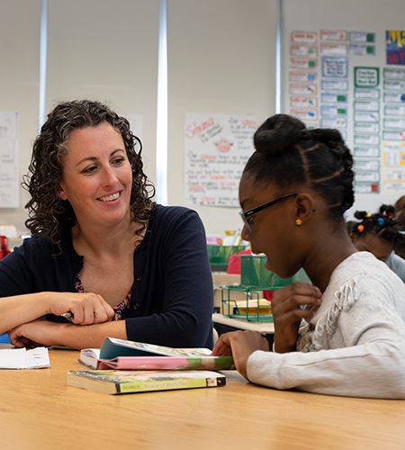 A teacher and student reading a book.